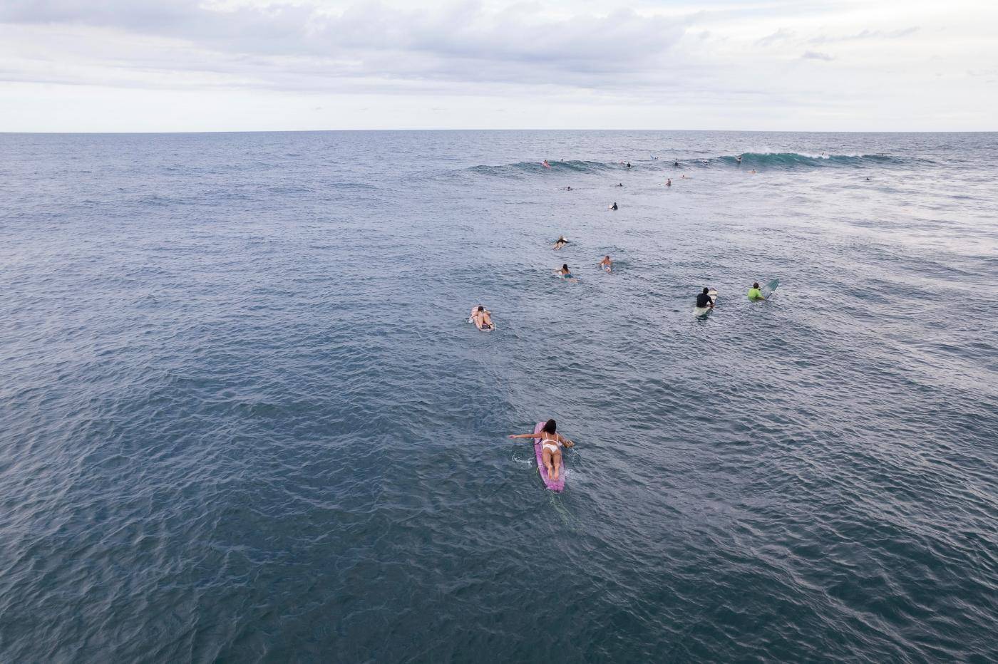 Surfers paddling out on a calm, open Pacific