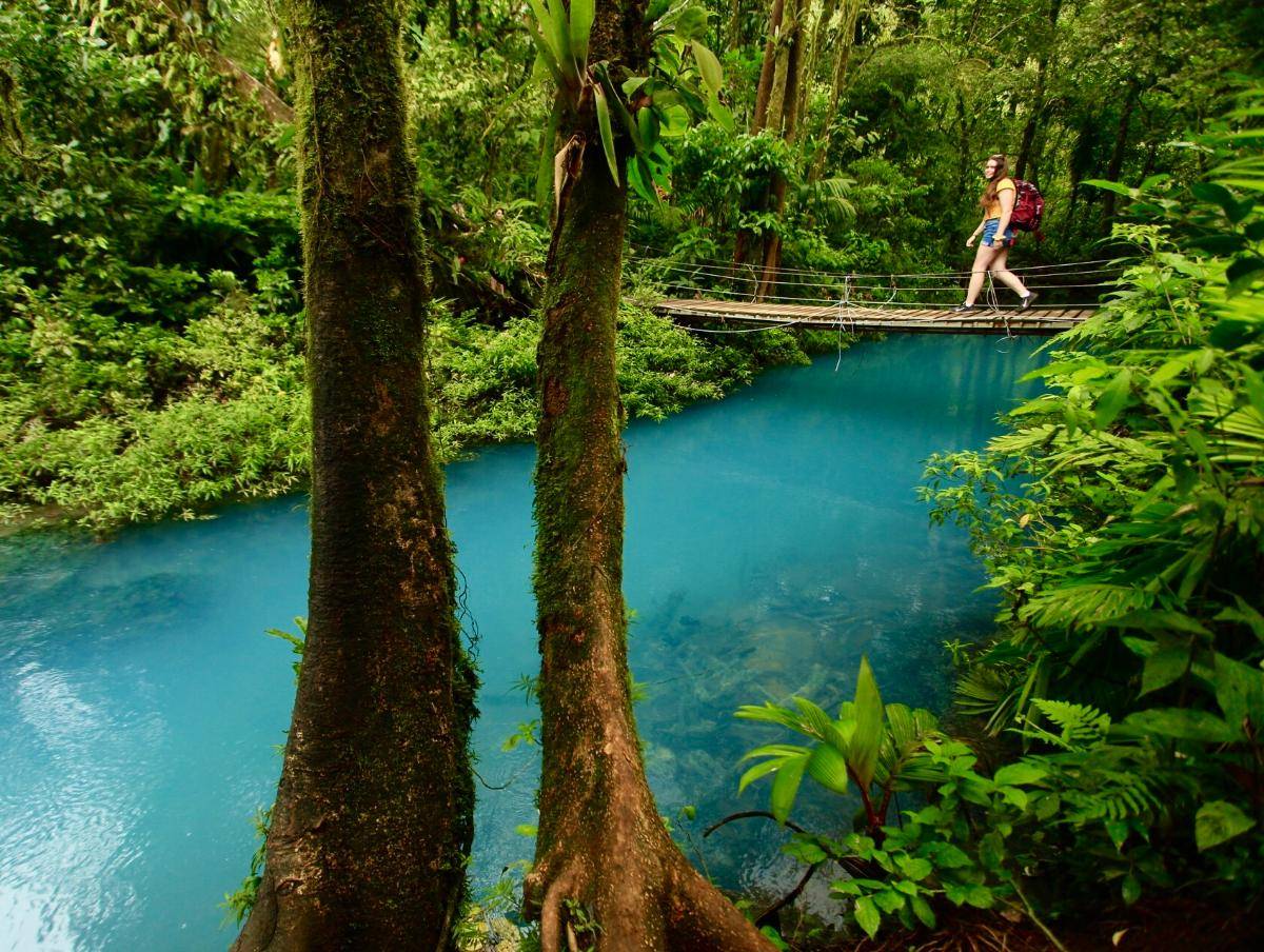 A hanging bridge over a bright turquoise forest river