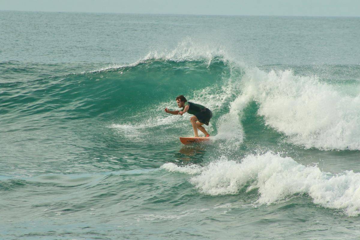A surfer riding a green Pacific wave