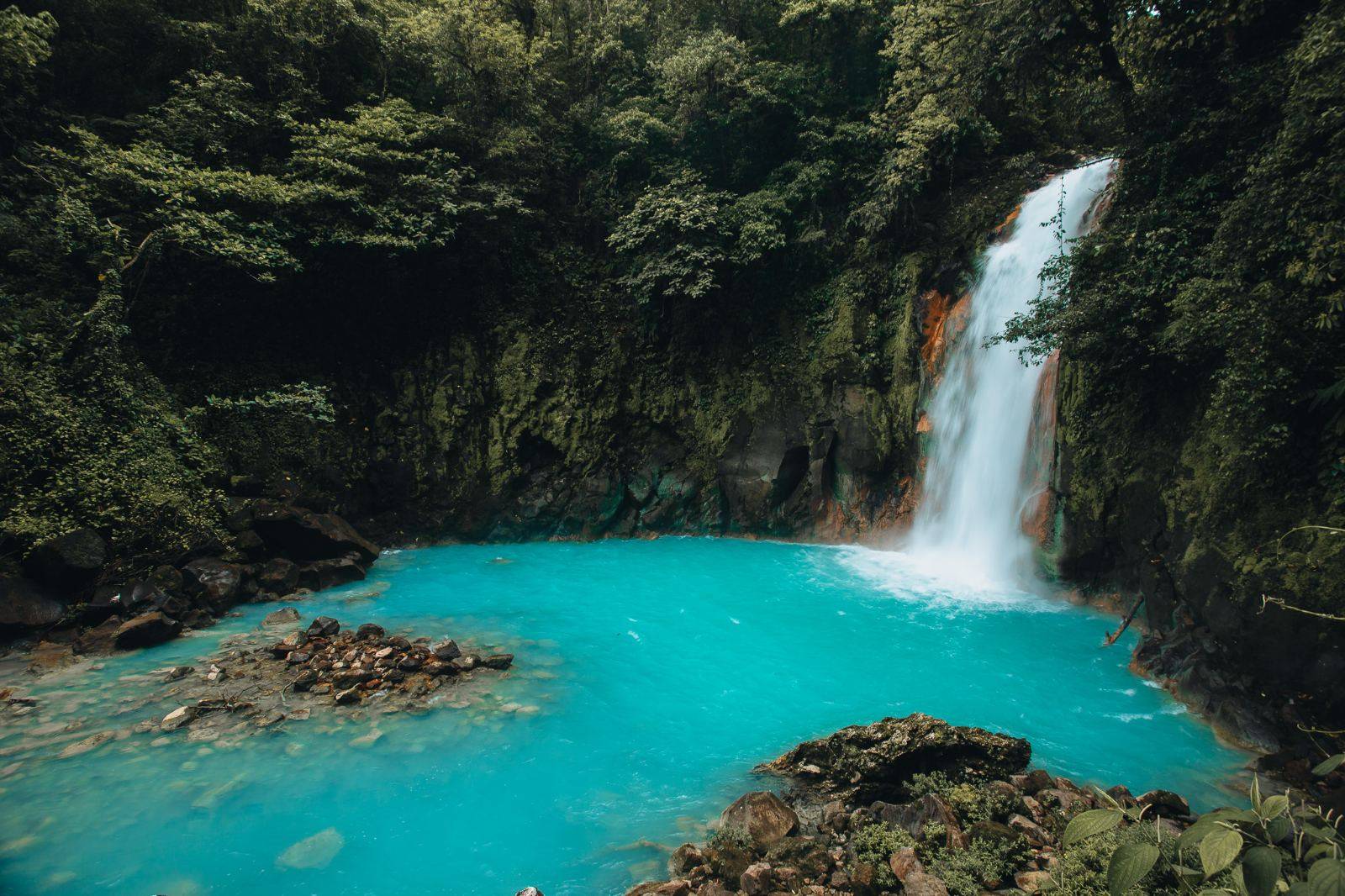 A waterfall pouring into a bright turquoise pool
